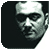 Pixelated grayscale portrait of a person with short dark hair, wearing a white headband, against a dark background with a light right edge.