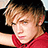 Pixelated image of a person with light brown hair wearing red clothing, set against bright pink background with white text.