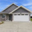 Static pixelated image of a single-story house with a white garage door, dark roof, and light-colored exterior walls under a blue sky.