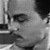 Black-and-white pixelated image of a person's face with visible eyes, nose, and mouth, showing partial hair and clothing details.