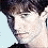 Pixelated close-up of a person's face with dark hair, light skin tone, and neutral expression against light blue background.