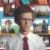 A pixelated static image of a person with dark hair and light skin wearing a white shirt and maroon tie, set against an indistinct background.