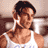 Pixelated static image of a person with dark hair wearing a white tank top, visible chest and shoulder muscles, against a blurred background.