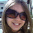 A pixelated close-up of a person with long brown hair wearing dark sunglasses and a light-colored headband, smiling against a blurred background.