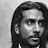 Black-and-white pixelated image of a person with long hair next to stylized text reading "Naveen" on a gray background.