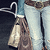 A pixelated static image shows a figure with long brown hair wearing a white top, holding a light-colored bag against a dark background.