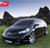 A pixelated image of a dark-colored sedan on grass with trees and a blue sky background, featuring a red banner in the top-left corner.