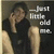 A person in a black shirt sits with one hand near their face, legs bent, against a dark background with text reading '...just little old me.'