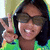 A person with dark hair and sunglasses makes a peace sign in three showing slight head movement