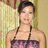 A pixelated image of a person with dark hair tied back, wearing a strapless dress with purple and pink patterns against a light-colored background.