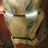 A metallic gold and red armored face with glowing white eyes, featuring a black text overlay reading IRONMAN in the top-right view.