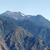 Pixelated landscape with blue mountains under a light blue sky, featuring subtle white highlights on mountain peaks.