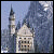 Pixelated static image of a light-colored building with a tall spire and domed roof against a blue sky background.