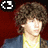 Pixelated image of a person with curly brown hair wearing a blue jacket over a yellow shirt against a red background, with red text reading "I'm bum, bum, burning up for you baby <3".
