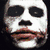 A four- of pixelated images showing a character with white face paint, dark eye makeup, and a wide red smile, wearing a dark suit and white shirt