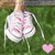 A static image of white sneakers on green grass with a pink heart, text, and heart-shaped hand gesture.