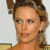 Pixelated close-up of a person with light brown hair styled in an updo, wearing a light-colored top against a pale background.