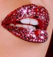 Close-up of lips covered in red and pink glitter with visible teeth, set against light skin background.