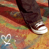 A close-up of a person's foot wearing a brown and white sneaker on a colorful patterned carpet with a white heart symbol.