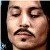 Pixelated close-up of a person's face with closed eyes, mustache, and dark hair against a dark background.
