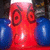 Red cartoon face with large blue circular ears, wide eyes, and a small smile against dark background.