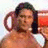 A pixelated image of a person with dark hair in a white bikini top, seated on an orange chair against a light background.