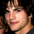 Pixelated close-up of a person with light brown hair, dark eyes, and pink lips against black background.