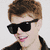Two pixelated images of a person with brown hair and black clothing, one wearing sunglasses smiling leftward, the other without sunglasses looking rightward.