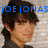 Pixelated image of a person with dark hair and light skin, overlaid with blue text reading 'joe jonas' against a gray background.
