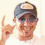 A person wearing a dark cap with a yellow and red patch, light-colored shirt, and sunglasses, making a finger gesture in three sequential poses.