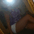 A person in a purple top and white shorts lies on their side against a wooden background with a bright light source.