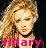 Pixelated image of a person with light brown curly hair wearing a pink top and dark choker necklace, set against a blurred background.