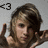 A person with light brown hair and fair skin makes a hand gesture near their face against a gray background, with the left hand raised in a peace sign.