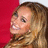 A woman with long light brown hair smiles against a red background, her head turning slightly left to right across frames.