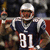Pixelated image of a football player in dark blue jersey with white number 81, holding trophy aloft against blurred background.