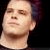 Pixelated close-up of a person's face with closed eyes, light skin tone, and dark hair against a black background.