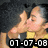 Two people in a close embrace, one in a yellow shirt and dark top, with a date stamp overlay.
