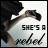 Pixelated static icon showing a partial figure with dark hair and light skin holding an object, accompanied by text reading "SHE'S A" above stylized cursive text on a white background.