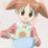 Two side-by-side animated frames of a cartoon character with brown hair, large eyes, and a light blue apron over pink sleeves holding a blue bowl.