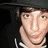 A person wearing a black hat and dark hoodie with white drawstrings, shown in a of four with subtle facial expression changes