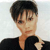 Pixelated static image of a person with short dark hair wearing a black top against a light background.