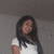 A pixelated image of a person with long dark hair wearing a white short-sleeve shirt against a gray background.