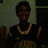 A pixelated static image shows a person wearing a dark top with a gold patterned lower section and a thick gold chain necklace against a muted background.