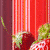 Animated strawberry icon with red fruit, green leaves, and white seeds against vertical striped background.