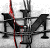 Pixelated static icon featuring abstract black and red shapes on a gray background with visible dithering and compression artifacts.