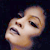 Pixelated close-up of a light-skinned face with closed eyes, mouth open in a grimace, against a dark background.