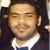 Static pixelated image of a person with short dark hair wearing a white collared shirt and dark jacket, face centered in frame.