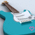 A turquoise electric guitar with a brown neck and white pickguard appears in four , each showing a heart symbol changing from pink to black outline