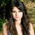 A pixelated static image shows a person with long dark hair wearing a sleeveless top against a blurred green and brown background.