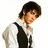Pixelated image of a person with short dark hair wearing a white shirt and black vest, standing against a plain white background.